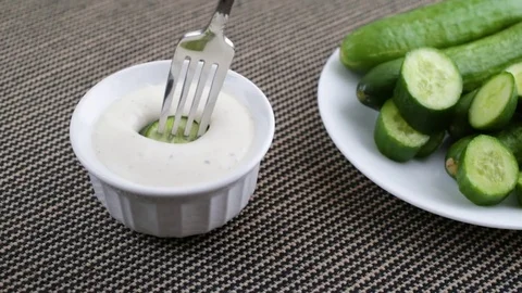 Slice of bite size cucumber being dipped in ranch dressing Stock Footage 82315065