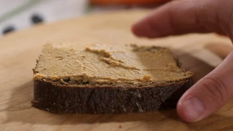 A slice of black rye bread with pate is taken by hand and taken away from the 스톡 동영상 233170738