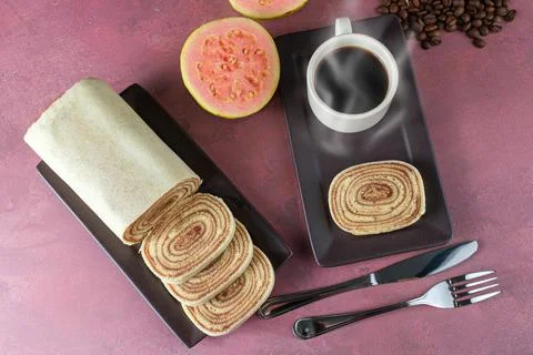 Slice of bolo de rolo surrounded by guava, cup and coffee beans on a red back Stock Photos