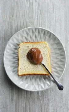 Slice of bread and spoonful of hazelnut praline paste on a plate Stock Photos