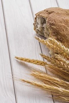 Slice of bread and wheat ears on white boards Stockfoto's