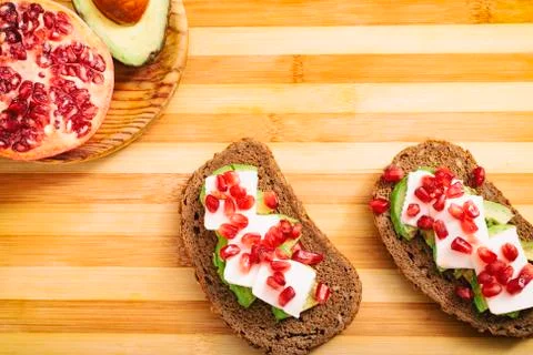 Slice of bread with avocado, cherry tomato, pomegranate seeds and fresh chees Stock Photos