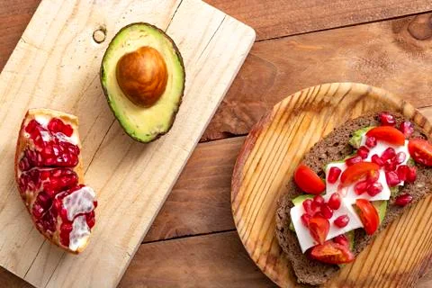 Slice of bread with avocado, cherry tomato, pomegranate seeds and fresh chees Stock Photos