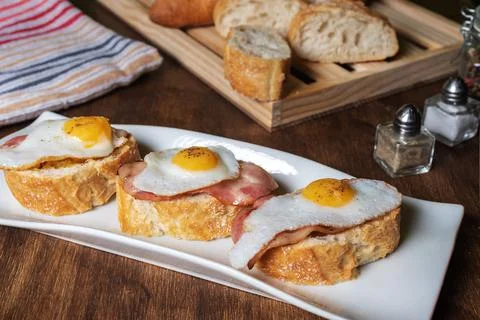 Slice of bread with bacon and grilled quail egg,on a wooden table. Stock Photos