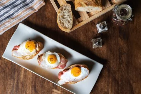 Slice of bread with bacon and grilled quail egg,on a wooden table. Stock Photos