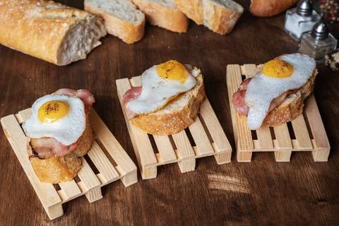 Slice of bread with bacon and grilled quail egg,on a wooden table. Stock Photos