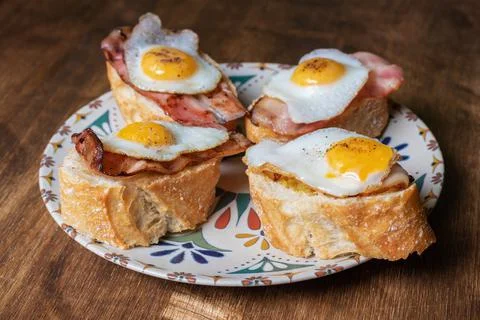Slice of bread with bacon and grilled quail egg,on a wooden table. Stock Photos