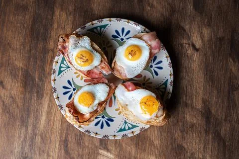 Slice of bread with bacon and grilled quail egg,on a wooden table. Stock Photos