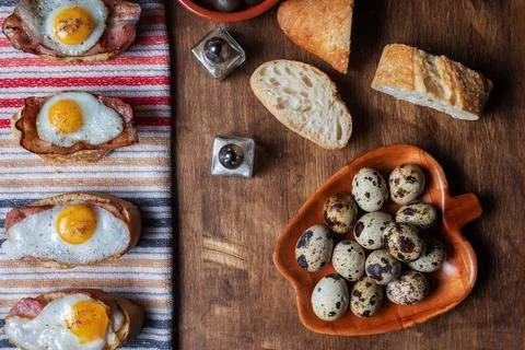 Slice of bread with bacon and grilled quail egg,on a wooden table. Stock Photos