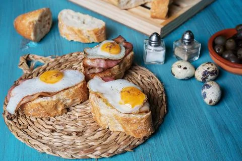 Slice of bread with bacon and grilled quail egg,on a wooden table. Stock Photos