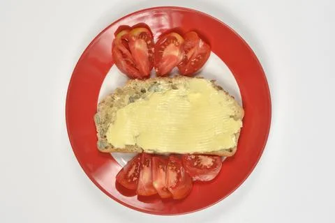 Slice of bread with butter and tomato slices on plate top view Фото