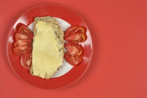 Slice of bread with butter and tomato slices on red background Stock Photos