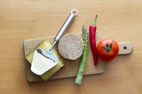 Slice of bread with cheese and chilli, tomato, asparagus, bun on chopping board Stock Photos