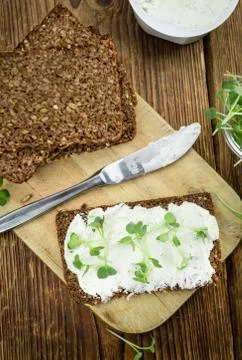 Slice of bread with fresh cutted cress and cream cheese on an old wooden tabl Stock Photos