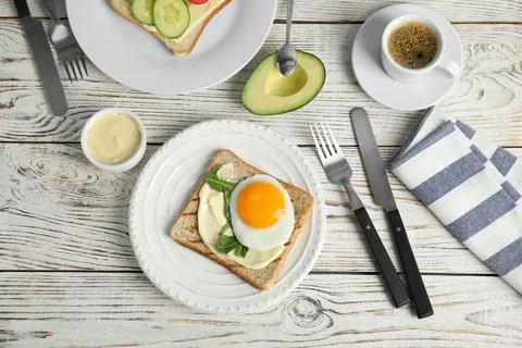 Slice of bread with fried egg, spread and arugula on white wooden table, flat Stock Photos