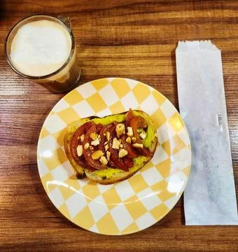 A slice of bread with guacamole, tomatoes and nuts on a checkered plate on a Stock Photos