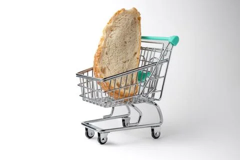 Slice of bread inside a miniature shopping cart on white background Stock Photos