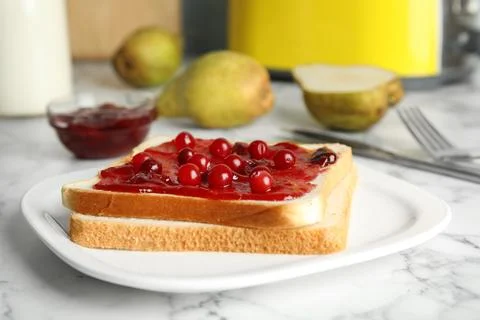 Slice of bread with jam on white marble table Stock Photos