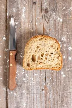Slice of bread with a knife on wooden background Stock Photos