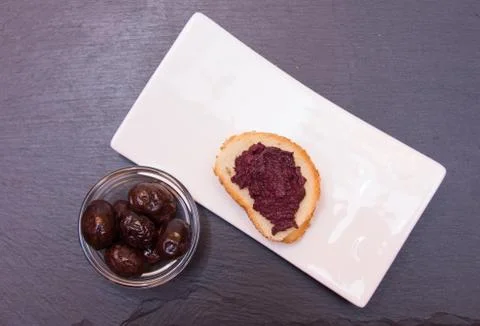 Slice of bread with olive paste on slate top view from above Stock Photos