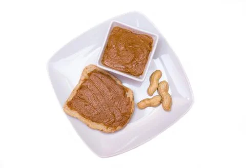Slice of bread with peanut butter on white background top view Stock Photos