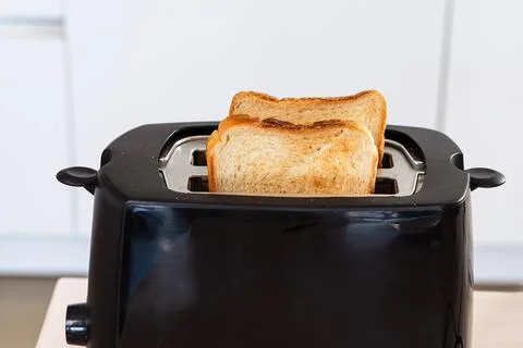 Slice of bread popping up from toaster, heating and toasting breakfast food,  Foto stock