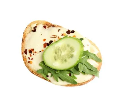 Slice of bread with spread, cucumber and arugula on white background, top vie Stock Photos