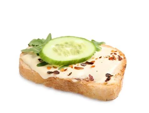 Slice of bread with spread, cucumber and arugula on white background Stock Photos