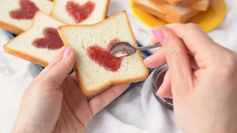 Slice of bread with strawberry jam in heart shape in the girl hand 動画素材 211429226