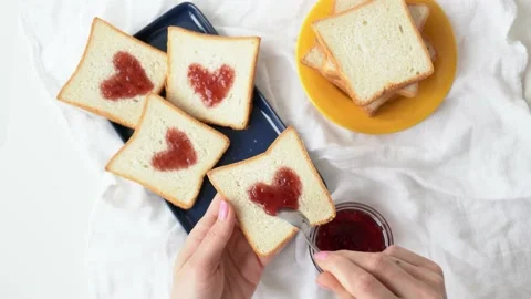 Slice of bread with strawberry jam in heart shape in the girl hand. Woman 動画素材 229721008