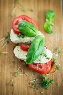 A slice of bread topped with tomatoes, vegan mozzarella and basil Stock Photos
