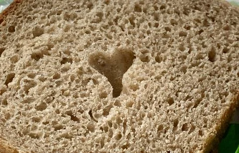 A slice of brown bread displays a heart-shaped hole in its center, discovered Stock Photos