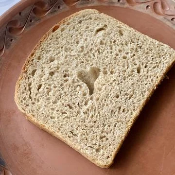 A slice of brown bread sits on a rustic plate, featuring a unique heart-shaped Stock Photos