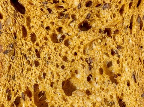 Slice of Brown Rye Fresh Bread with grains as background, top view. Macro Clo Stock Photos