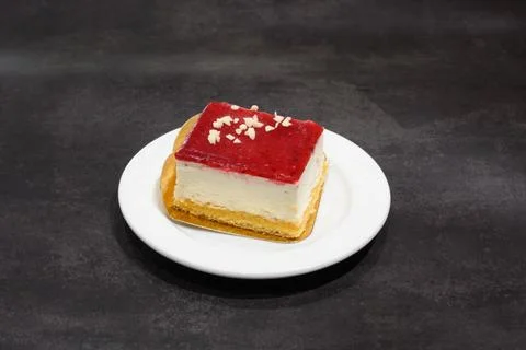 A slice of cake with a cherry on top sits on a white plate 스톡 사진