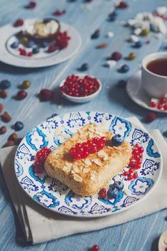 Slice of cake with red berries on a blue patterned plate Stock Photos