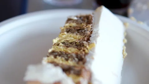 Slice of cake with white cream and chocolate on white disposable plate close up Stock Footage 346176277