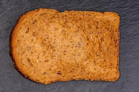 Slice of cereal brown bread on slate plate, top view Stock Photos