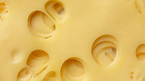 Slice of cheese with holes top view, rotation. Traditional Swiss cheese Stock Footage 241210553
