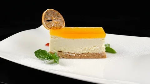 Slice of Cheesecake decorated with caramelized orange, mint leaf, red jam Stock Footage 90660691