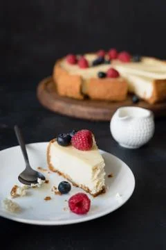 Slice of cheesecake with missing bite on white plate Stock Photos
