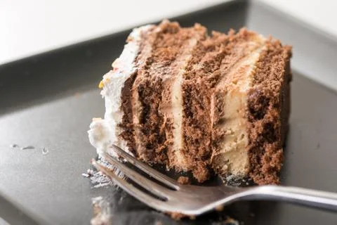 Slice of chocolate cake on the black plate with metal fork Stock Photos