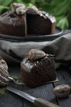 Slice of chocolate cake with date on dark black wooden table. Stock Photos