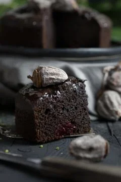 Slice of chocolate cake with date on dark black wooden table. Green leaves .. Foto stock