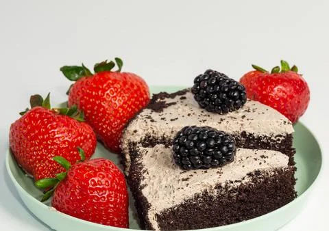 A slice of chocolate cake with forest berries and strawberries. Stock Photos
