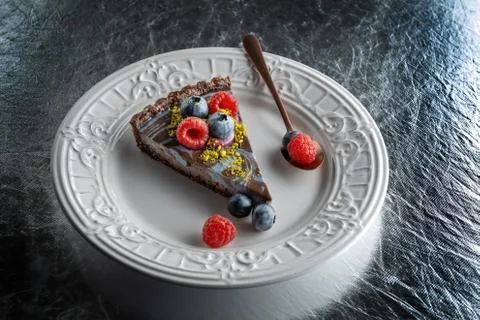 Slice of chocolate cake with nuts, decorated with berries, blueberries and 스톡 사진