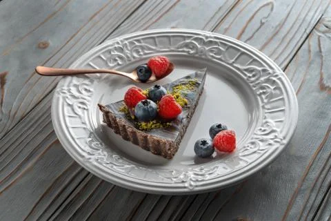 Slice of chocolate cake with nuts, decorated with berries, blueberries and Фото