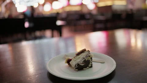 Slice of chocolate cake on paper plate with fork in softly blurred cafe interior Vidéo 345267272