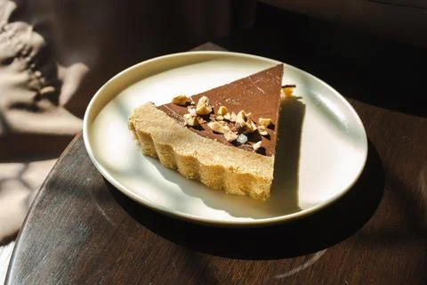 A slice of chocolate cake with walnuts on top of a white plate Stock Photos
