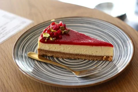 Slice of classic raspberry cheesecake with pistachios on plate Stock Photos
